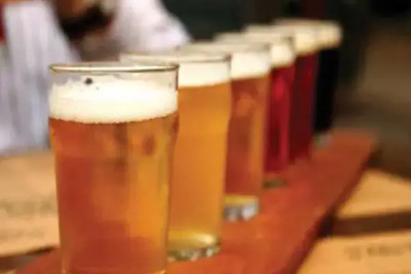 Mehrere frisch gezapfte Biergläser auf einem Holzbrett